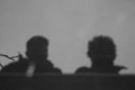 Black and white silhouette of two people against a textured wall.