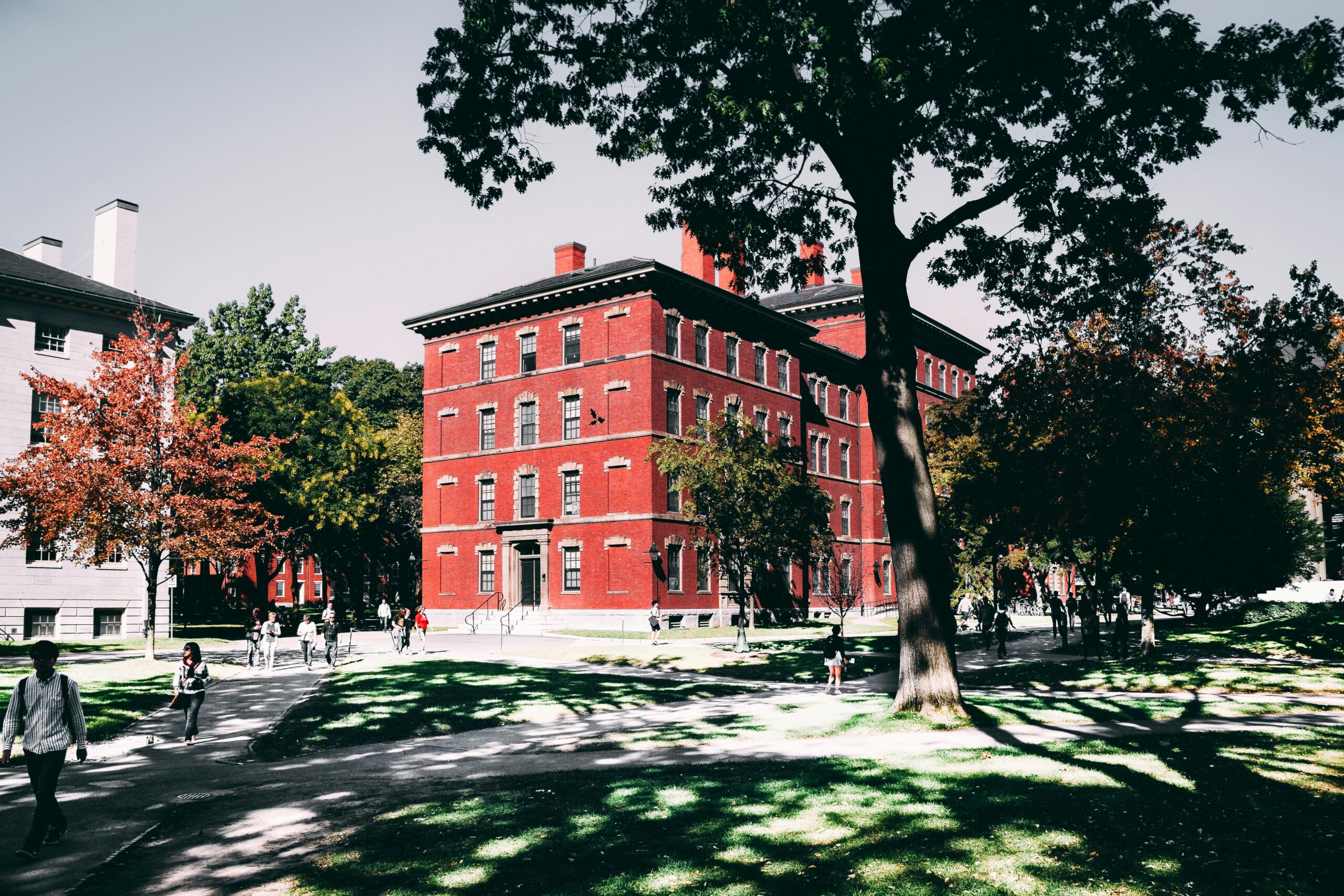 View of a historic red brick university building surrounded by lush trees and walking paths.